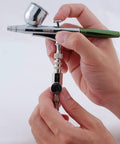 Hands holding MAC Valve With Quick Connect Coupler And Plug For Universal Airbrush Control On Any Brand Airbrush Easy Quick Swap