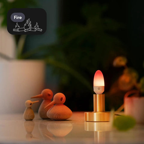 E12 Candle Color Wi Fi Smart LED Light Bulb with Polychrome in a cozy room setting, bulb glowing in warm hues.