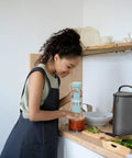 Custom Snug Storage Sleeve For KitchenAid Hand Blender KHBV53 Dishwasher Safe Arm Guard Holder With Jar Lid Pouch Sleek Grey beside user blending in kitchen.