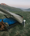 Heavy Duty Tent Stakes and Pegs Kit with Windproof Ropes and Hammer Storage Bag Included for Camping Hiking Beach Shelters Easy Install Durable Outdoor Gear for Tough Campouts securing tent on grass with dog laying beside