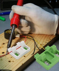 User setting Electric Wire Welding Fixture Clamp Adjustable Soldering Jig For Precise Alignment In MIG TIG And Spot Welds Heat Resistant Insulation Durable Pro Grade Workhorse Easy Setup For Shop Pros Green White Finish on wooden board, shown in use.
