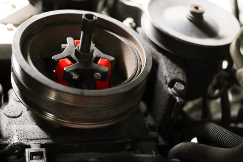 Harmonic Balancer Puller Kit for cars and trucks with adjustable 3-jaw design in use inside a tight engine compartment