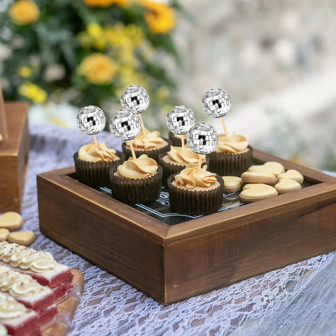 Cupcakes with silver disco ball cupcake toppers for 70s theme birthday party and New Year celebrations on a wooden tray