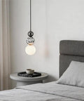 Aolyzmt Natural Alabaster Marble Pendant Light, Modern Cylinder LED Hanging Lamp above a bedside table in a bedroom.