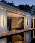 Outdoor LED Wall Light 31.5 Inch Black Sconce With Rectangular Acrylic Panel illuminating a modern patio exterior at night.