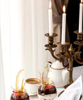 Front view of antique brass candelabra with multiple arms and white candles on a dining table