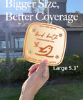 Copper Disk Bird Bath Purifier For Clean Water All Season, 5.3 inch wide, held outdoors against a house view.