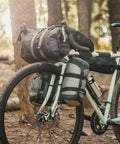 Bike with VersaCage Adventure Cage with Adjustable Mounting System and VersaMount Clamps and Straps for Dry Bags on forest trail