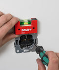 Sola Spirit Level Compact Go! Clip, 0 being used to level an electrical socket with a screwdriver in hand.