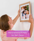 Woman hanging a frame with family photo puzzle on wall, labeled 'Personalized Puzzle for Wall Decor'