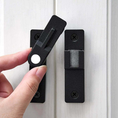Close-up of a Matte Black 180 Degree Flip Latch Set For Barn Doors And Sliding Doors, two-pack, zinc alloy with luminous finish, being installed.