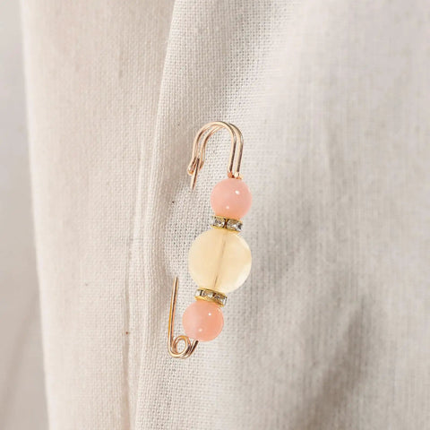 Close-up of a 12 Piece Heavy Duty Alloy Waist Adjustment Pin With Beads on a Fabric Surface for Fixing Baggy Jeans.