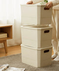 Person stacking beige storage bins with handles in a room; alternative to Six Pack Plastic Storage Bins With Lids For Closet Shelves And Desktop