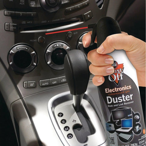 Hand using Two Pack 10 Oz Compressed Gas Dusters for quick cleaning of car interior near gear shift, blows away dust lint and debris.