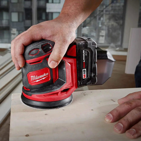 Slick Cordless Random Orbit Sander Kit With M18 Battery Pack for smooth wood finishing in use on flat surface.