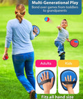 Child playing Toss And Catch Ball Game With Four Sticky Paddles For Kids in a park, demonstrating multi-generational play fun.