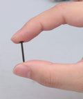 Close-up of hand holding a Black Round Head Miniature Wood Screw Nail, 0.71 inch long, ideal for furniture decor and DIY projects.