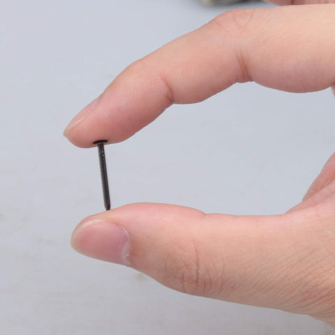 Close-up of hand holding a Black Round Head Miniature Wood Screw Nail, 0.71 inch long, ideal for furniture decor and DIY projects.