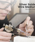 Person using hard silver solder wire with torch on jewelry ring, 75% silver content