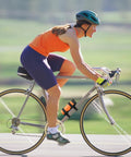 Cyclist using Adjustable Strap Speaker Mount For Bike, Golf Cart, And Boat Rails on bike frame, holding JBL Charge 5 securely.