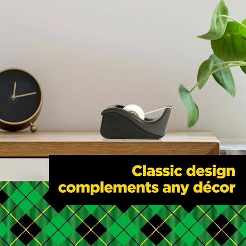 Deluxe Black Desktop Tape Dispenser With Weighted Non Skid Base for one handed dispensing on a shelf next to a clock and plant