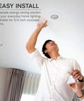Man installing Four Pack LED PAR30 Flood Light Bulbs 75W Equivalent 5000K Bright White in recessed ceiling fixture indoors.