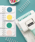 Mini Cinch Binding Tool For DIY Books And Notebooks With Wire Or Spiral Coils Pro Grade Mini Binding Machine near colored paper samples.