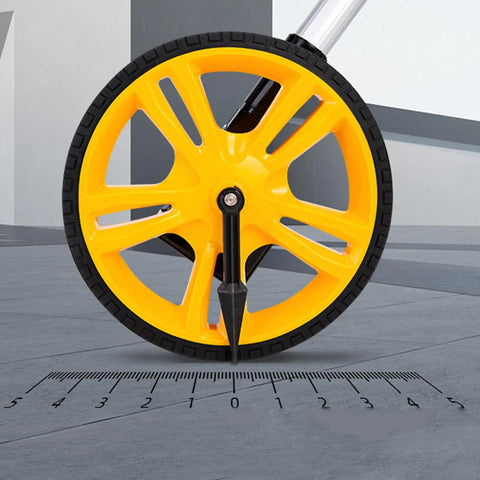 Close-up of the yellow wheel of Measuring Wheel 0-9999.9m Digital Display for Construction Worker on a measuring scale.