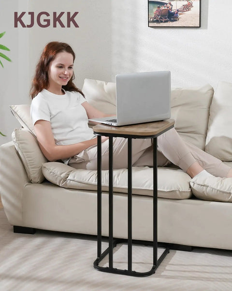 Woman using C Shaped End Table For Sofa And Bed, Slim 27 Inch High Side Table That Slides Under Couch, in Greige and Black Finish.