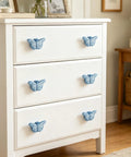White dresser featuring Six Piece Ceramic Drawer Knobs Set with Cute Butterfly Cabinet Pulls for nursery and kid friendly rooms.