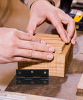 Hands assembling wooden box with slick black stainless steel butt hinges foldable with screws, flat opening design for cabinet doors.