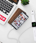 Wireless charging pad next to smartphone and smartwatch, showing 77% charge, with laptop in background, modern workspace.