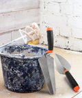 4 Pack Pro Grade Masonry Hand Tools Set with 6 Inch Pointing Trowels and 9 Inch Gauging Trowels next to plaster bucket
