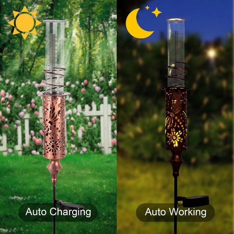 Solar Powered Rain Gauge With LED Night Light Outdoor Garden Stake Decoration 7 Inch Plastic Tube Freeze Proof Copper Metal Finish Brown Yard Gauge for Lawn and Weather Tracking in a garden, showing day and night use.