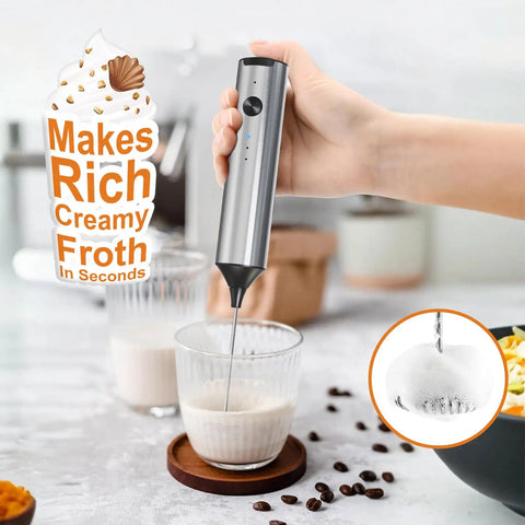 Rechargeable Handheld Milk Frother With Stainless Steel Stand Three Speeds Electric Milk Whisk For Latte And Cappuccino Cordless Coffee Mixer With Type C Charging Easy One Touch Frothing For Barista Quality Drinks in use, making frothy milk in a glass cup.