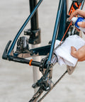 Person maintaining bike with Dummy Hub Axle Chain Keeper For 12mm Thru Axle And QR Frames installed on rear triangle.