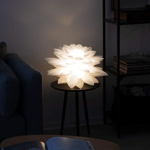 Ambiently lit Dope Puzzle Pendant Lamp Shade Lotus Flower DIY Jigsaw Kit For Hanging Ceiling Light Or Floor Lamp White 20 Inch Diameter on a table.