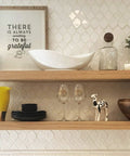 Wooden shelves with dishes and decor, including a framed quote and plants, against a patterned wall in a kitchen setting.