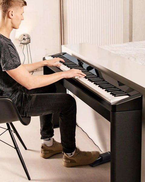Man playing digital piano with sustain pedal for keyboards and digital pianos with polarity switch one quarter inch input