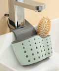 Double Deck Faucet Mount Kitchen Sink Organizer With Adjustable TPR Rubber Sponge Soap And Scrubber Storage Basket above a sink, in mint green.