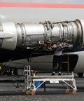 Aircraft engine removal with technician on ladder, showcasing detailed mechanics and structure, for maintenance.