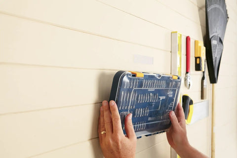 Hands using Extreme Interlocking Fasteners 4 Strips 1x3 Inches for heavy-duty bonding with tool case on wall.