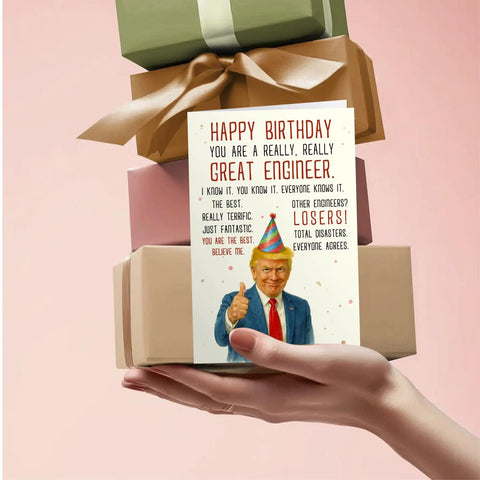 Funny Engineer Birthday Card For Men, Nerdy Yet Heartfelt Greeting Card with colorful design held in front of wrapped gifts.
