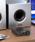 M03 200 Watt Subwoofer Amplifier With TPA3255 For Home Theater on a desk next to silver subwoofers and laptop