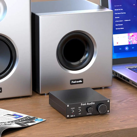 M03 200 Watt Subwoofer Amplifier With TPA3255 For Home Theater on a desk next to silver subwoofers and laptop