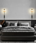 Dope Black Globe Shade Wall Sconces Set Of 2 with black metal frame and glass lampshades, illuminating a modern bedroom setting.