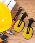 Heavy Duty Hard Hat Mounted Ear Muffs Built To Kill Loud Workshop Racket On Construction Zones And Factory Floors Dependable Industrial Hearing Safety Armor with yellow caps and black clips beside tools.