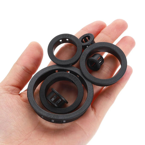 Hand holding 15 Pack Round Cable Snap Bushing Grommets One And Quarter Inch 32mm Black Snap In Cable Grommet Protectors