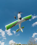 TrainStar 500mm Brushless RC Plane Ready To Fly With 6 Axis Gyro flying against a blue sky, showing green wings and white body.