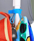 Stainless Steel Umbrella Hook For Beach Gear And Towel Bag Holder Keeps Sand Off Tables And Surfaces Patio Accessory Fits All Standard Umbrella Poles Includes Clear Adapter For Skinny Poles Made In USA Blue holding hats and towels.